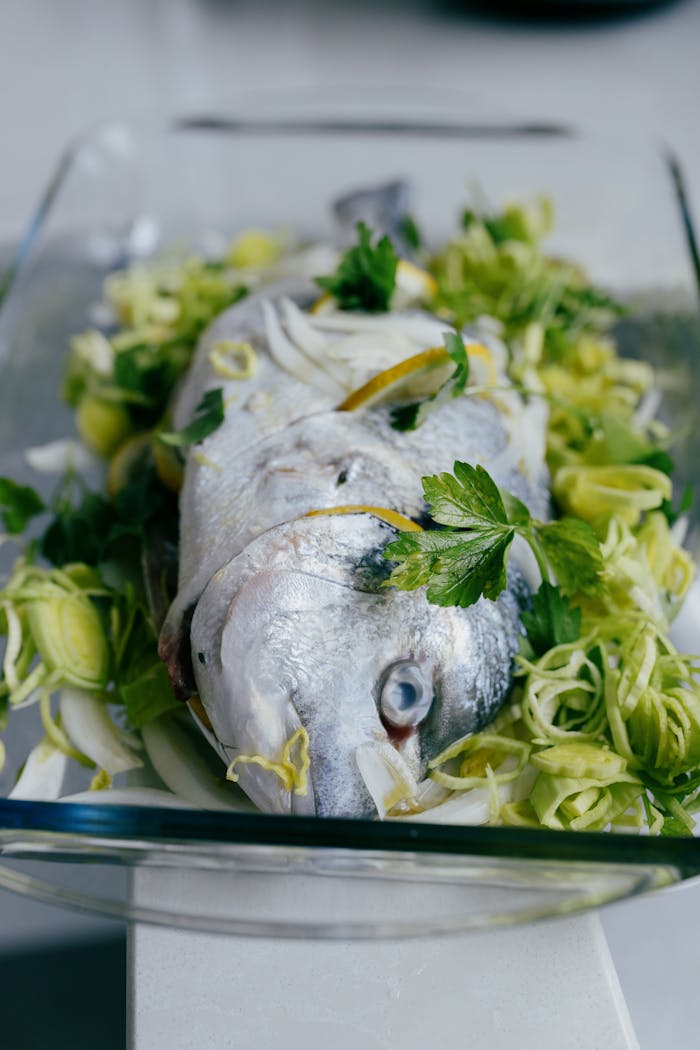 Delicious dorado fish prepared with fresh herbs and vegetables in a glass dish, ready for baking.